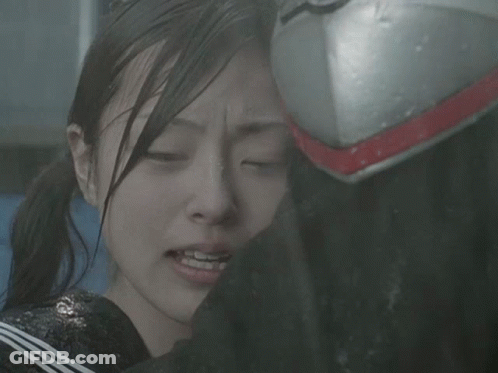 A Girl With Her Eyes Closed Is Being Comforted By A Person Wearing A Helmet GIF