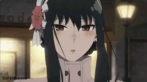 A Girl With Long Black Hair And A Flower In Her Hair Looks At The Camera GIF