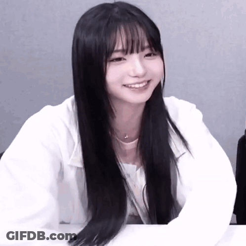 A Girl With Long Black Hair And Bangs Is Smiling GIF