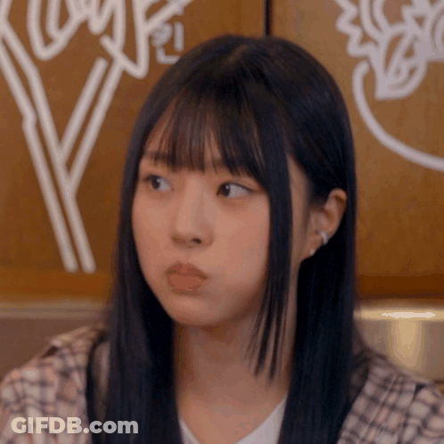 A Girl With Long Black Hair And Bangs Looks To The Side GIF