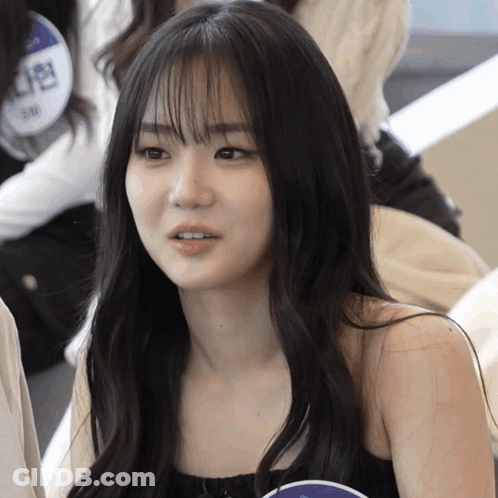 A Girl With Long Black Hair Has A Name Tag That Says 5/8 On It GIF