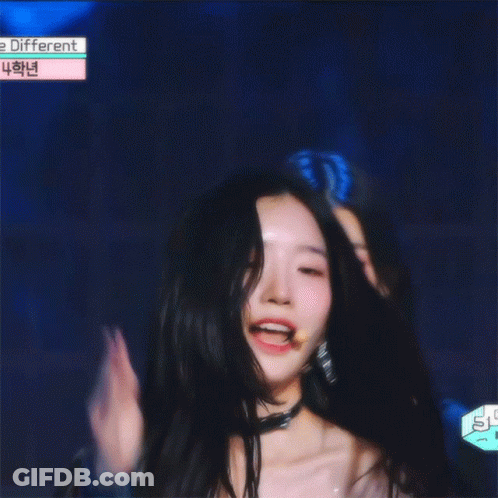 A Girl With Long Black Hair Is Smiling In Front Of A Sign That Says ' E Different ' GIF