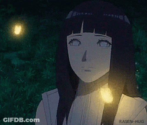 A Girl With Long Black Hair Is Standing In The Grass With A Light Shining On Her Face . GIF