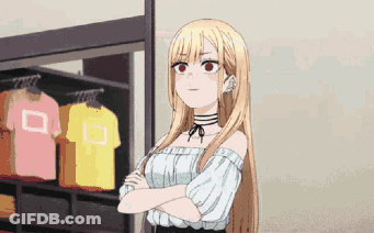 A Girl With Long Blonde Hair Is Standing With Her Arms Crossed In Front Of A Clothes Rack . GIF