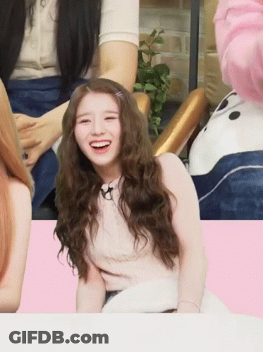 A Girl With Long Curly Hair Is Smiling In Front Of A Panda Bear GIF