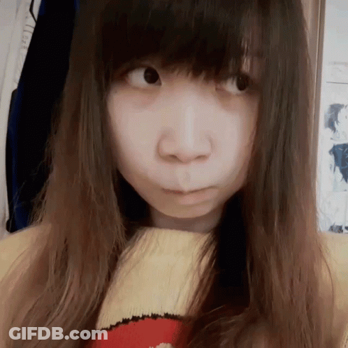 A Girl With Long Hair Is Wearing A Yellow And Red Sweater And Making A Face GIF
