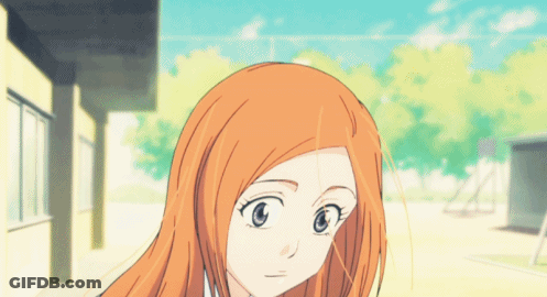 A Girl With Long Orange Hair And Blue Eyes Is Standing In Front Of A Building GIF