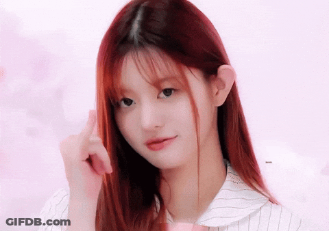 A Girl With Long Red Hair Is Looking At The Camera And Pointing At Her Hair GIF