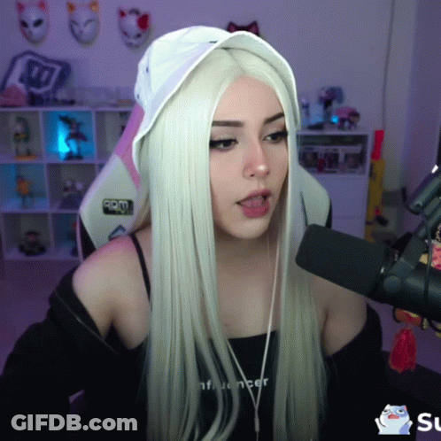A Girl With Long White Hair Is Talking Into A Microphone While Wearing A Black Top That Says Influencer GIF