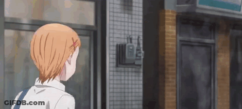 A Girl With Orange Hair Is Standing In Front Of A Store And Looking Out The Window . GIF