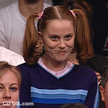 A Girl With Pigtails And Braces On Her Teeth Is Making A Funny Face While Sitting In A Crowd . GIF