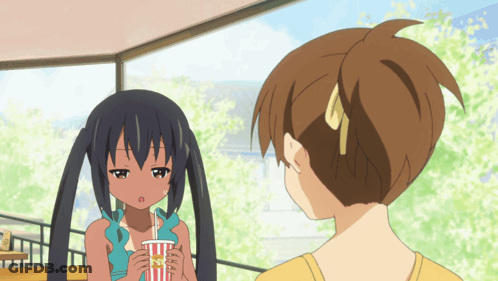 A Girl With Pigtails Is Holding A Cup That Says " Popcorn " On It GIF
