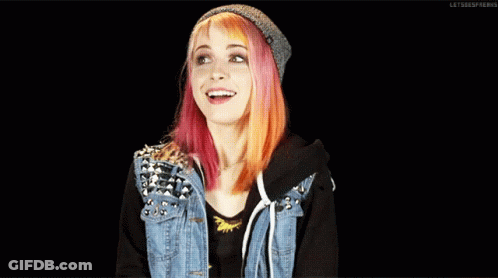 A Girl With Pink And Orange Hair Wearing A Denim Jacket And A Beanie GIF
