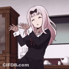 A Girl With Pink Hair And A Bow On Her Head Is Dancing In Front Of A Cabinet . GIF