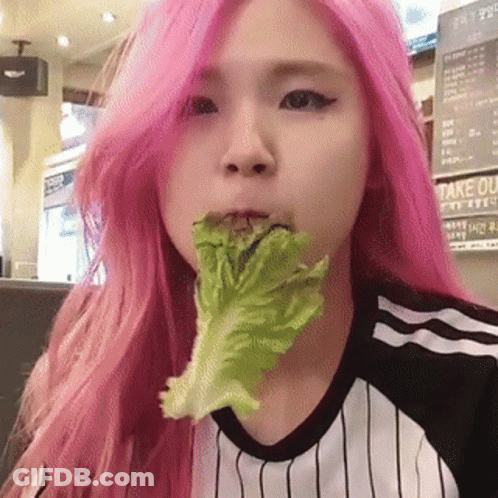 A Girl With Pink Hair Is Eating Lettuce In A Restaurant GIF