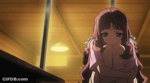 A Girl With Pink Hair Is Hugging Her Knees In A Dark Room GIF