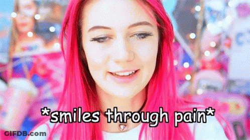 A Girl With Pink Hair Is Smiling With The Words * Smiles Through Pain * Below Her GIF