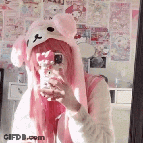 A Girl With Pink Hair Is Taking A Selfie In A Mirror While Wearing A Pink Hat . GIF