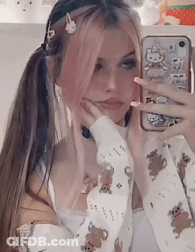 A Girl With Pink Hair Is Taking A Selfie In Front Of A Mirror . GIF
