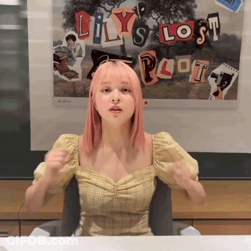 A Girl With Pink Hair Sitting In Front Of A Poster That Says Lily 'S Lost Plot GIF