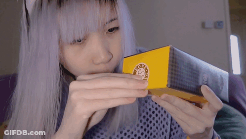 A Girl With Purple Hair Is Holding A Box With A Sticker On It That Says ' Good Day ' GIF
