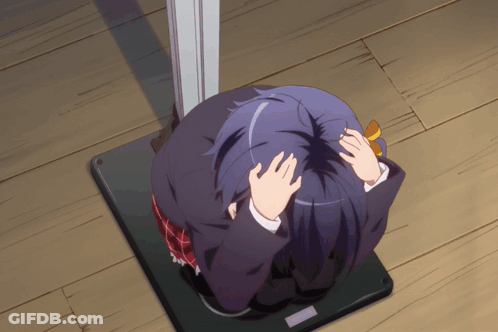 A Girl With Purple Hair Is Sitting On A Wooden Floor Covering Her Face With Her Hands GIF