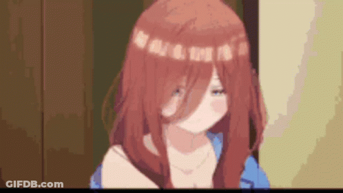 A Girl With Red Hair And A Blue Shirt Is Standing In A Room With A Blurred Background . GIF