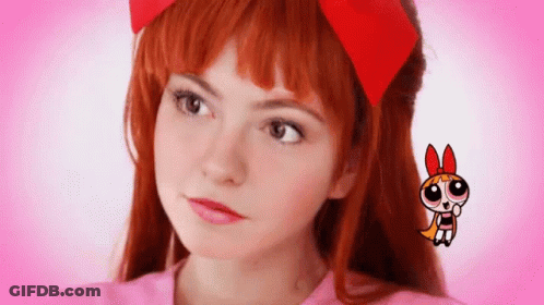 A Girl With Red Hair And A Red Bow On Her Head Is Wearing A Pink Shirt . GIF