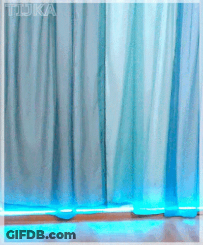 A Girl With Red Hair And Glasses Stands In Front Of A Blue Curtain With The Word Tdka Written On It GIF