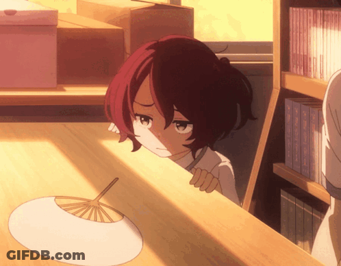 A Girl With Red Hair Is Peeking Over A Wooden Table GIF