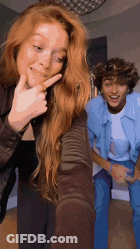 A Girl With Red Hair Is Taking A Selfie With A Boy . GIF