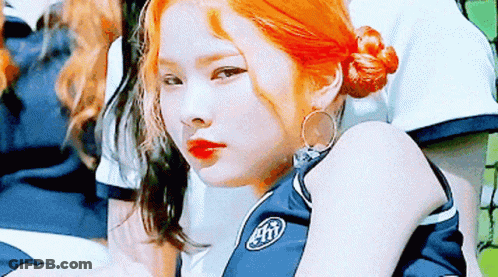 A Girl With Red Hair Is Wearing A Blue Shirt With The Letter T On It . GIF