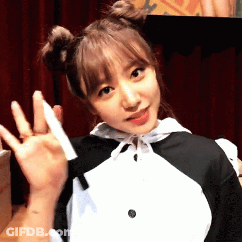 A Girl With Two Buns On Her Hair Is Waving Her Hand GIF