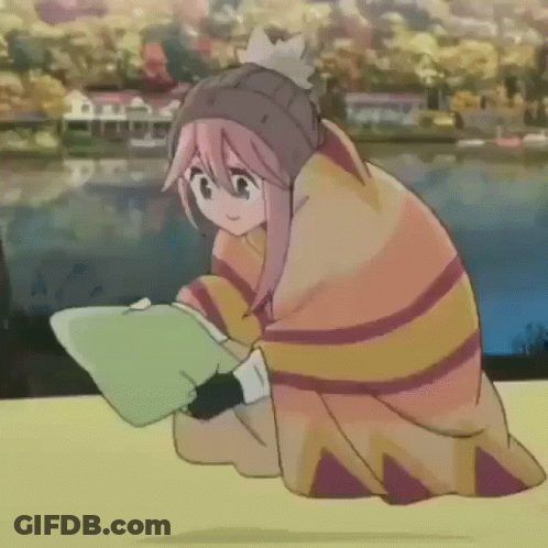 A Girl Wrapped In A Blanket Is Sitting On A Table Reading A Book . GIF