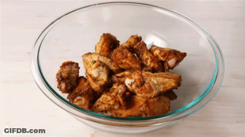 A Glass Bowl Filled With Fried Chicken Wings With The Word Delish On The Bottom GIF