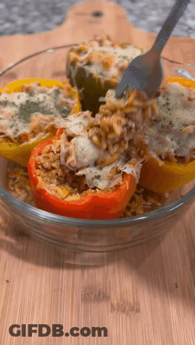 A Glass Bowl Of Stuffed Peppers With Rice And Cheese GIF