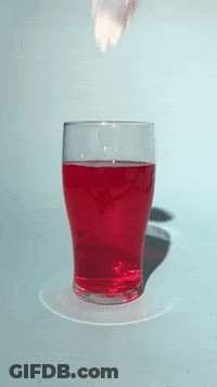 A Glass Filled With Red Liquid With A Strawberry Splashing Out Of It GIF