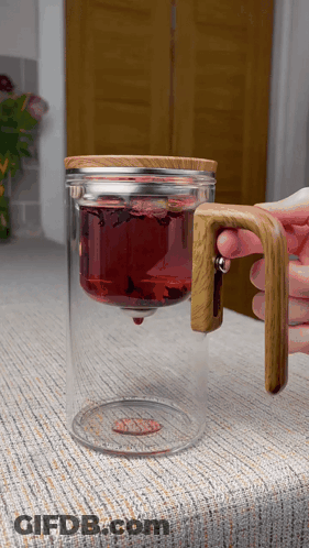 A Glass Mug With A Wooden Handle And A Lid That Says ' Oasis ' On It GIF