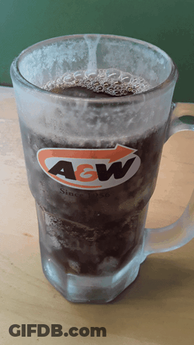 A Glass Of A&w Soda Is Sitting On A Wooden Table GIF