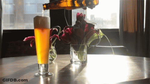 A Glass Of Beer Is Being Poured From A Bottle GIF