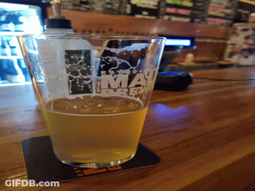A Glass Of Beer Sits On A Coaster That Says Miami Brew GIF