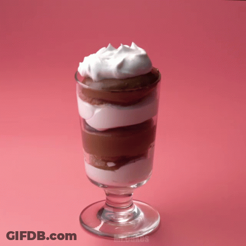 A Glass Of Chocolate Mousse With Whipped Cream On Top Of It GIF