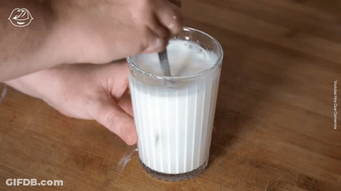 A Glass Of Milk Is Stirred With A Spoon GIF