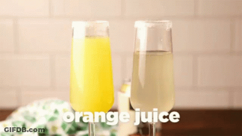 A Glass Of Orange Juice Is Being Poured Into A Glass Of Wine GIF
