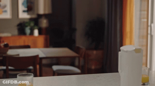 A Glass Of Orange Juice Sits On A Counter Next To A Pitcher Of Orange Juice GIF