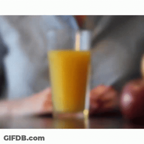 A Glass Of Orange Juice Sitting On A Table GIF