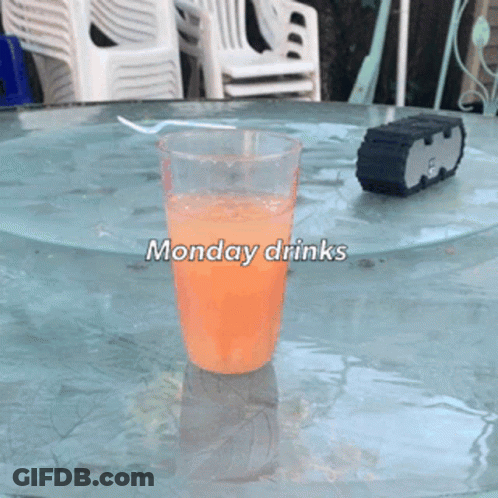 A Glass Of Orange Liquid On A Table With The Words Monday Drinks GIF