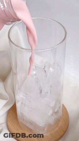 A Glass Of Pink Liquid Is Being Poured Into Ice GIF