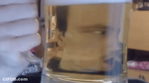 A Glass Of Water Is Sitting On A Table In Front Of A Window GIF