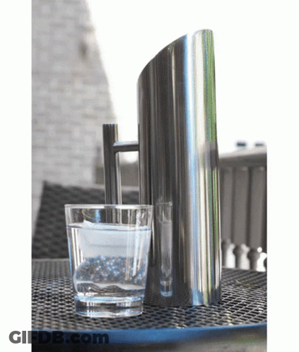 A Glass Of Water Sits Next To A Pitcher On A Table GIF